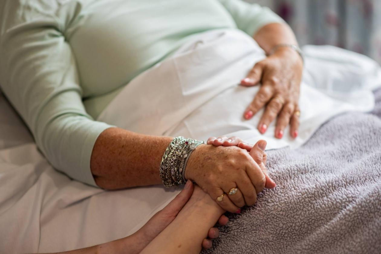 Hospice patient holding hands with a loved one